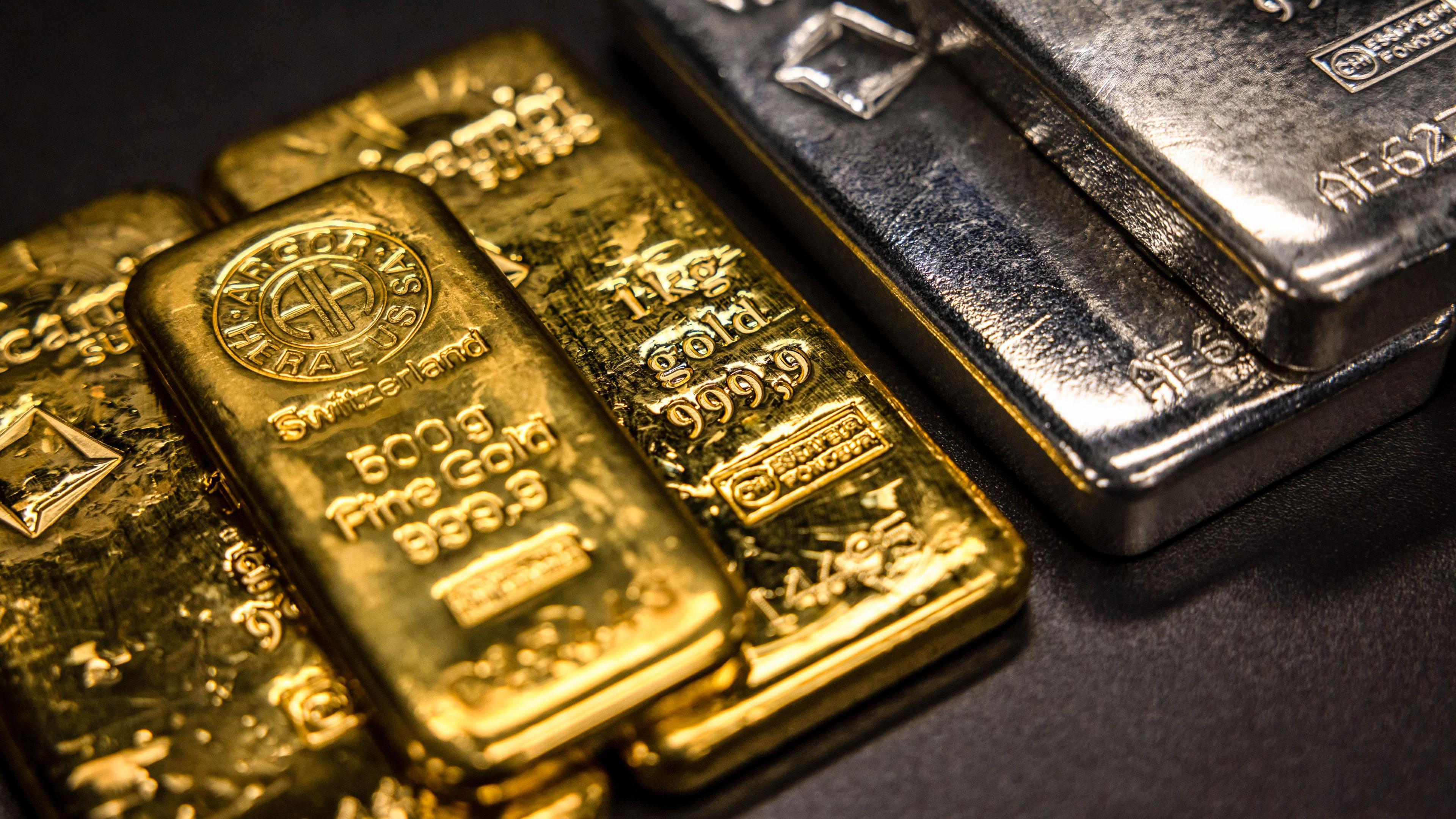 One kilogram and a five hundred gram gold bars next to one kilogram silver bars at The Vaults Group gold dealers.