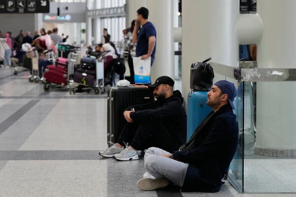 Two passengers sitting on the floor with their suitcases nearby at the airport in Beirut, Lebanon.