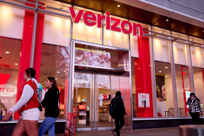 Verizon store in New York with its bright red logo and people walking past it.